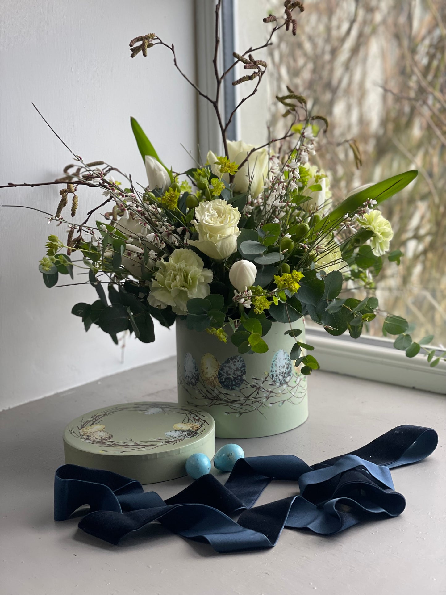 Hat box arrangement with seasonal blooms